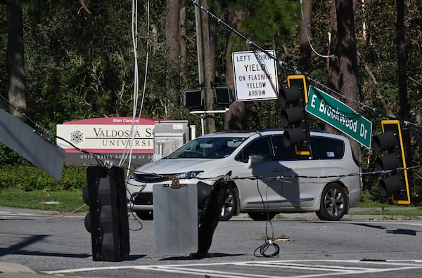 A car drives by fallen traffic signals and wires near Valdosta State University, Saturday, September 28, 2024, in Valdosta. The devastation in Valdosta was extensive after the South Georgia city was battered with hurricane-force winds on Helene’s path across the state. Damaging Helene has swept through Georgia, leading to at least 15 deaths. All 159 counties are now assessing the devastation and working to rebuild, even as serious flooding risks linger. Hyosub Shin/AJC