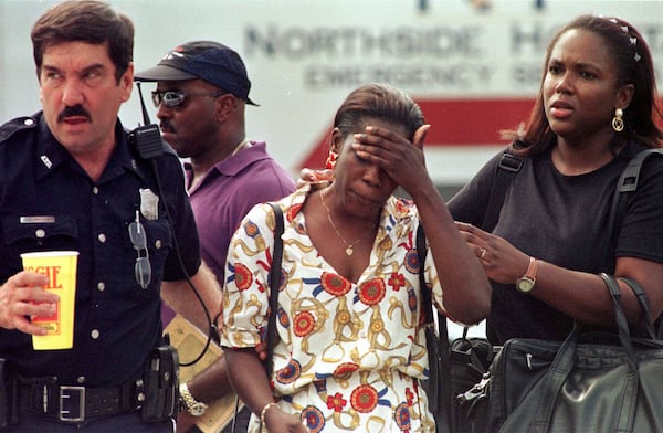 An unidentified woman is led away from the Buckhead office complex area after suspect Mark Barton opened fire in two office buildings, killing nine people and wounding 13 others.