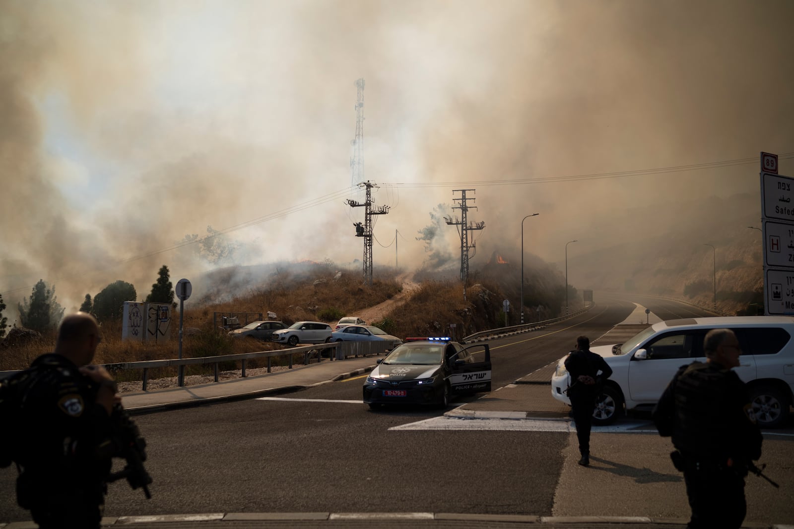 Israeli police officers stand next to a site of a fire after a rocket, fired from Lebanon, hit an area near the town of Rosh Pinna, northern Israel, Sunday, Oct. 20, 2024. (AP Photo/Leo Correa)