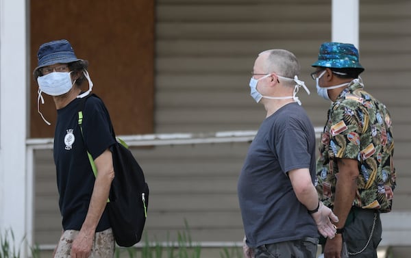 People wearing masks wait in line to receive free groceries at the first of five pop-up grocery stores provided by the Atlanta Hawks, Goodr, and State Farm at At-Promise Youth Center during the COVID-19 crisis, Friday, March 20, 2020. BRANDEN CAMP/SPECIAL