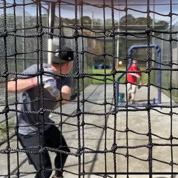 Former Georgia star Aaron Schunk (L), a minor leaguer in the Colorado Rockies organization, hits batting practice off throws from his father, Eric, in a batting cage at Medlock Park in Decatur. (Family photo)