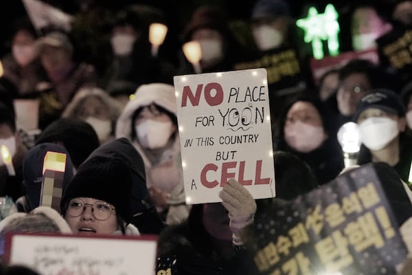 A participant holds a paper during a rally to demand South Korean President Yoon Suk Yeol's impeachment outside the National Assembly in Seoul, South Korea, Friday, Dec. 13, 2024. (AP Photo/Ahnn Young-joon)