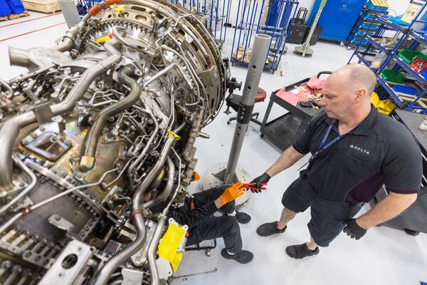 Airframe and Power Plant mechanics work on a Gear Turbine engine in Delta's new facility Tuesday, Feb. 7, 2023.  (Steve Schaefer/steve.schaefer@ajc.com)