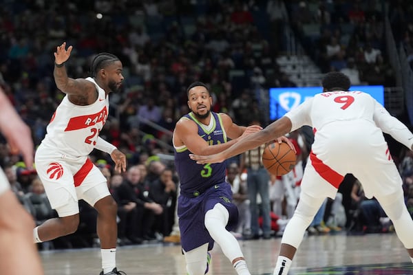 New Orleans Pelicans guard CJ McCollum (3) drives to the basket between Toronto Raptors guard Jamal Shead and guard RJ Barrett (9) in the second half of an NBA basketball game in New Orleans, Wednesday, Nov. 27, 2024. The Raptors won 119-93. (AP Photo/Gerald Herbert)