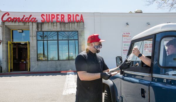 Andy Palerino, Superica’s Director of Operations, delivered a takeout order and plastic cutlery to Elliot Dennis, right, on March 25. Dennis and his father usually meet every other week at the restaurant. After first shutting down its dining room but offering takeout, Superica completely closed March 26, along with all of Rocket Farm Restaurant group’s other restaurants. (Jenni Girtman for The Atlanta Journal Constitution)