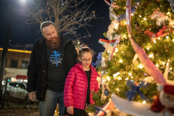 Xavier Ashe, left, looks at a decorated holiday tree with his daughter Emily Ashe, 10, at Marietta Square. (BRANDEN CAMP FOR THE ATLANTA JOURNAL-CONSTITUTION)