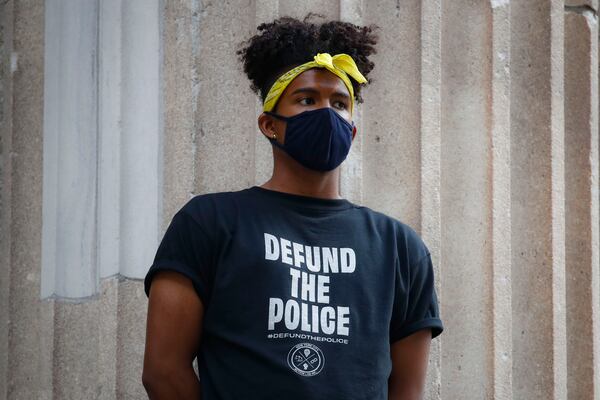 A protester stands on the steps of a government building near an encampment outside City Hall.