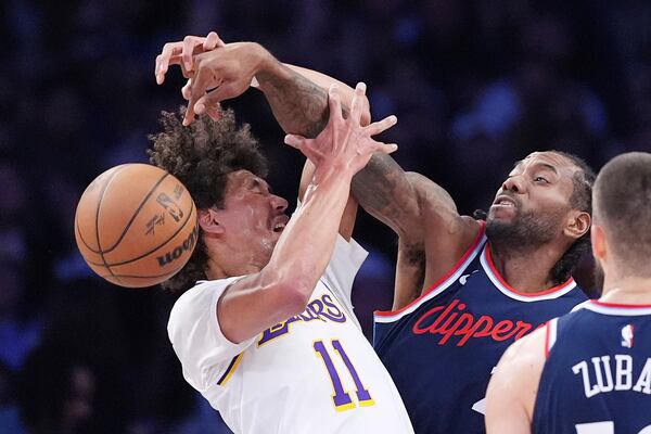 Los Angeles Clippers forward Kawhi Leonard, center, knocks the ball from the hands of Los Angeles Lakers center Jaxson Hayes during the first half of an NBA basketball game Sunday, March 2, 2025, in Los Angeles. (AP Photo/Mark J. Terrill)