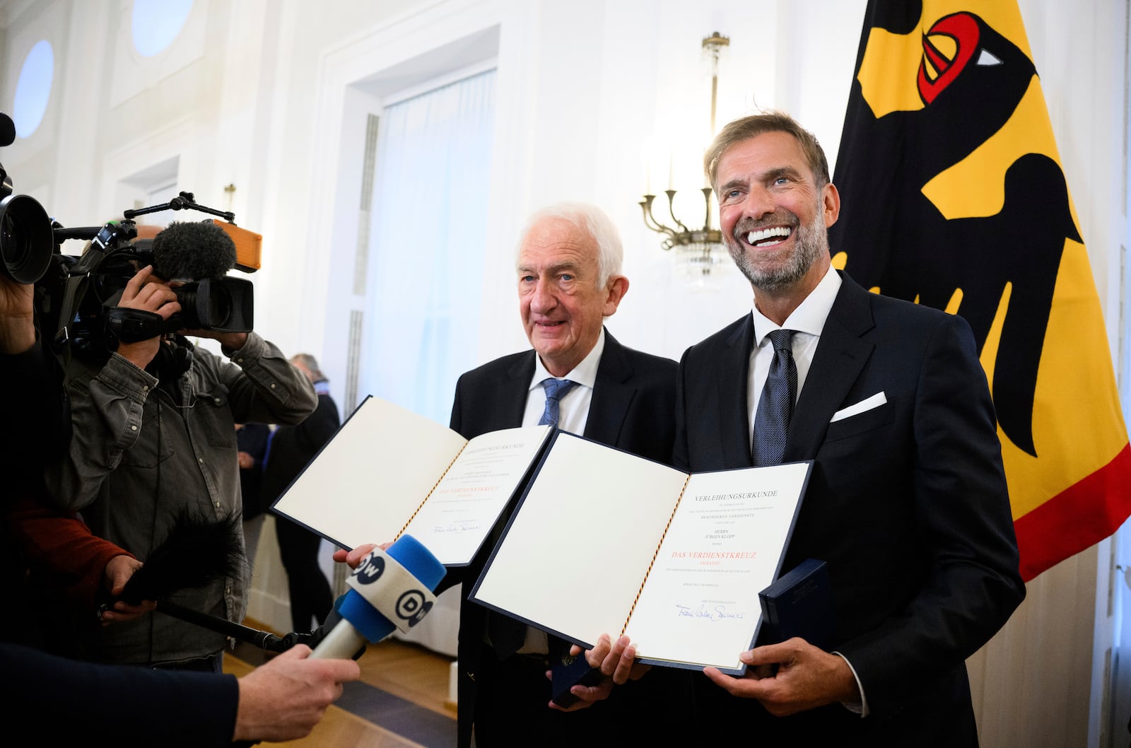 Johann Georg Goldammer and Jurgen Klopp stand in Bellevue Palace after receiving the Order of Merit of the Federal Republic of Germany and show their certificates as Federal President Steinmeier honors 28 citizens on the Day of German Unity, in Berlin, Tuesday, Oct. 1, 2024. (Bernd von Jutrczenka/dpa via AP)