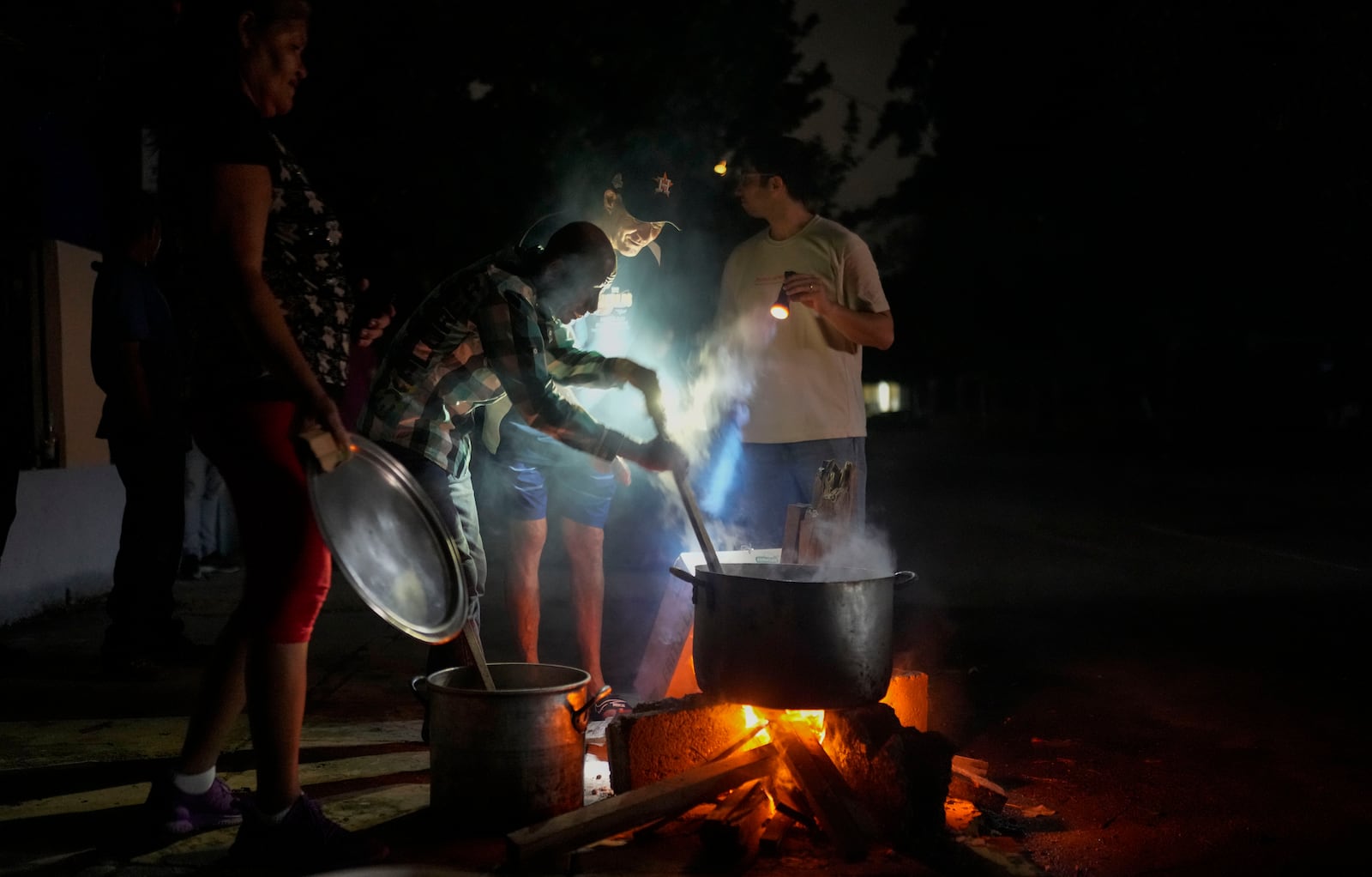 Residents prepare a soup over an open fire during a blackout following the failure of a major power plant in Havana, Cuba, Saturday, Oct. 19, 2024. (AP Photo/Ramon Espinosa)