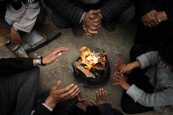 Members of Abed family, warm up by a fire at a tent camp for displaced Palestinians at the Muwasi, Rafah, southern Gaza Strip, Monday, Feb. 24, 2025. (AP Photo/Jehad Alshrafi)