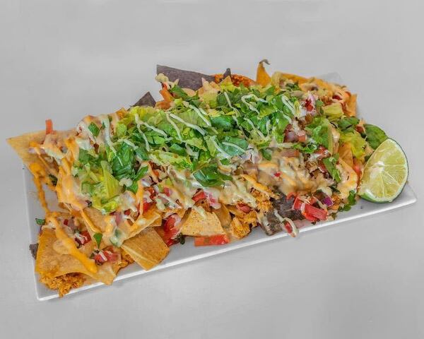 The nachos at Barrio ATL are a giant pile of chips, layered with melted queso, guacamole, pico de gallo and sour cream. Courtesy of Barrio ATL