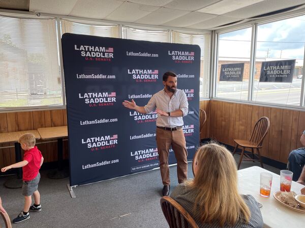 Senate candidate Latham Saddler addresses a crowd in Nashville, Ga. as his son Bubba wanders the room.