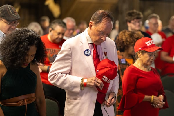 Republican attendees pray during a presidential debate watch party at gun store and indoor shooting range Adventure Outdoor in Smyrna on Tuesday, September 10, 2024. Candidates Vice President Kamala Harris and President Donald Trump are debating in Philadelphia. (Arvin Temkar / AJC)