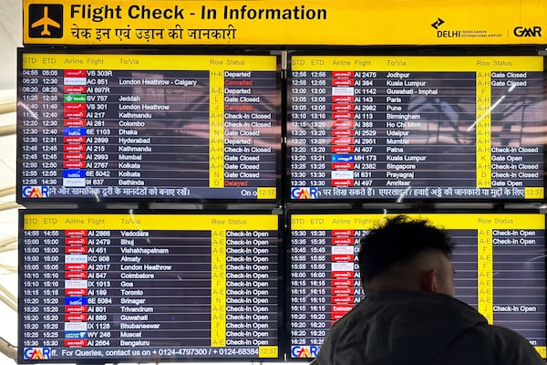 A passenger stands in front of a flight information screen showing cancelled flights destined for the Heathrow Airport in London, at the Indira Gandhi International Airport, in New Delhi, India, Friday, March 21, 2025. (AP Photo/Shonal Ganguly)