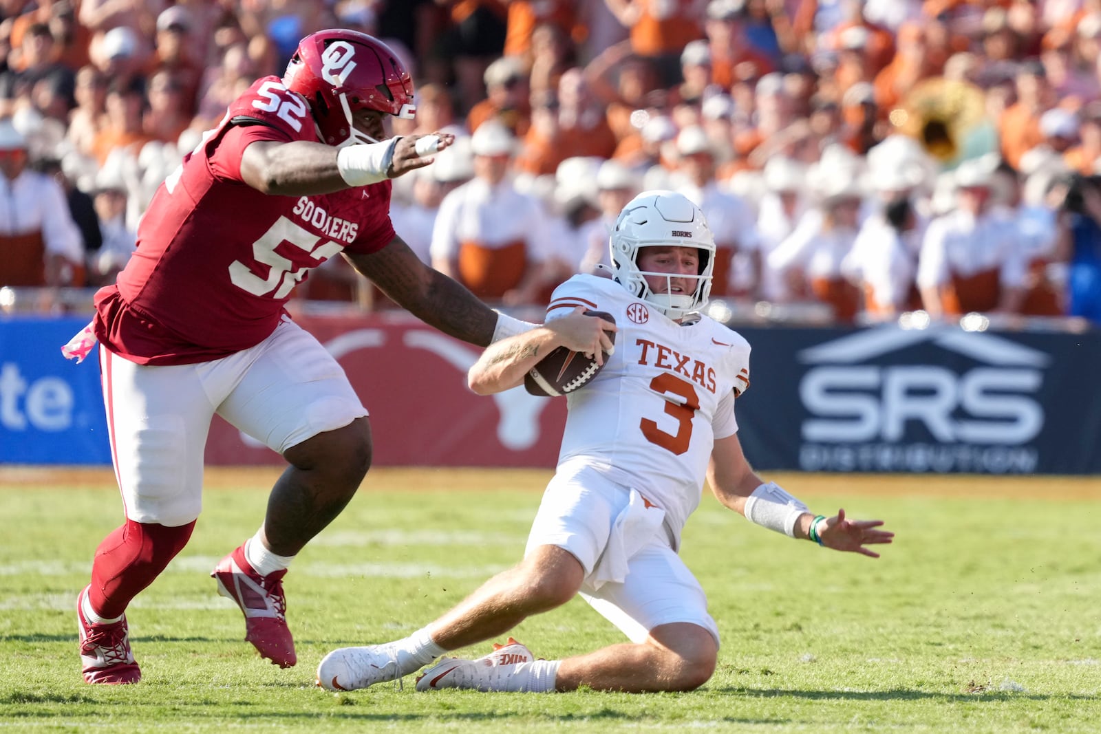 Texas quarterback Quinn Ewers (3) slides to the ground after a gain of yards as Oklahoma defensive lineman Damonic Williams (52) pressures in the second half of an NCAA college football game in Dallas, Saturday, Oct. 12, 2024. (AP Photo/Jeffrey McWhorter)