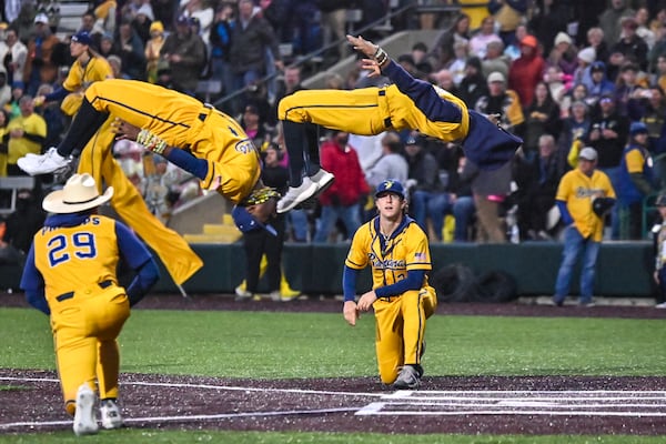 Savannah Bananas players execute backflips at home plate during the first home game of the 2025 season on Friday at Grayson Stadium in Savannah. Sarah Peacock for the AJC