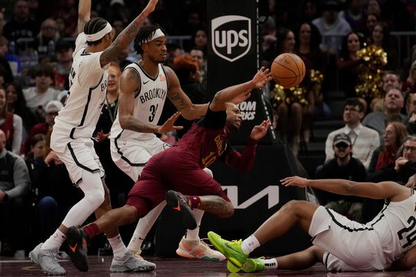 Cleveland Cavaliers guard Darius Garland, center, passes between Brooklyn Nets guard Keon Johnson, left, Nic Claxton, second from left, and Cam Thomas (24) in the second half of an NBA basketball game, Tuesday, March 11, 2025, in Cleveland. (AP Photo/Sue Ogrocki)