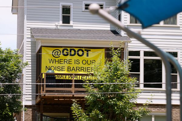 A large yellow sign that reads “@GDOT Where is our Noise Barrier” hangs on the deck of a home overlooking the I-285/Ga. 400 construction.  (Natrice Miller / natrice.miller@ajc.com)

