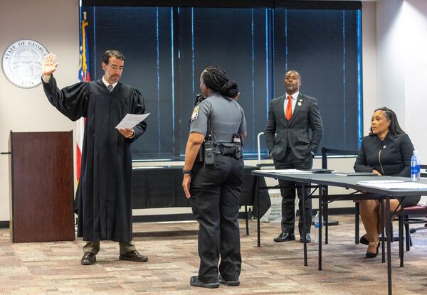 Judge Robert McBurney (left) swears in a bailiff in the Jury Assembly Room at Fulton County Courthouse in Atlanta on Tuesday, July 11, 2023 as Fulton County District Attorney Fani Willis (right) looks on. Two Fulton County grand juries are being selected, one of which will be expected to decide whether to hand up an indictment in the long-running investigation into alleged meddling with the 2020 presidential election. (Arvin Temkar / arvin.temkar@ajc.com)