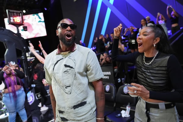 Former basketball player Dwayne Wade, center, and actor Gabrielle Union, right, cheer as Rose defeats Laces in an Unrivaled 3-on-3 basketball semifinal, Sunday, March 16, 2025, in Medley, Fla. (AP Photo/Rebecca Blackwell)