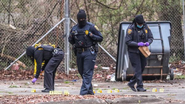 College Park police mark evidence at the edge of a parking lot near a wood line outside the Super 8 motel on Old National Highway.