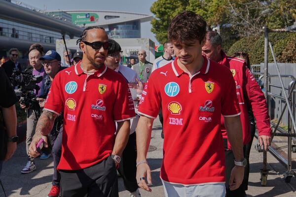 Ferrari driver Lewis Hamilton of Britain, left, chats with his teammate Charles Leclerc of Monaco as they walk out from their team's hospitality suite ahead of the Chinese Formula One Grand Prix, in Shanghai, China, Friday, March 21, 2025. (AP Photo/Andy Wong)