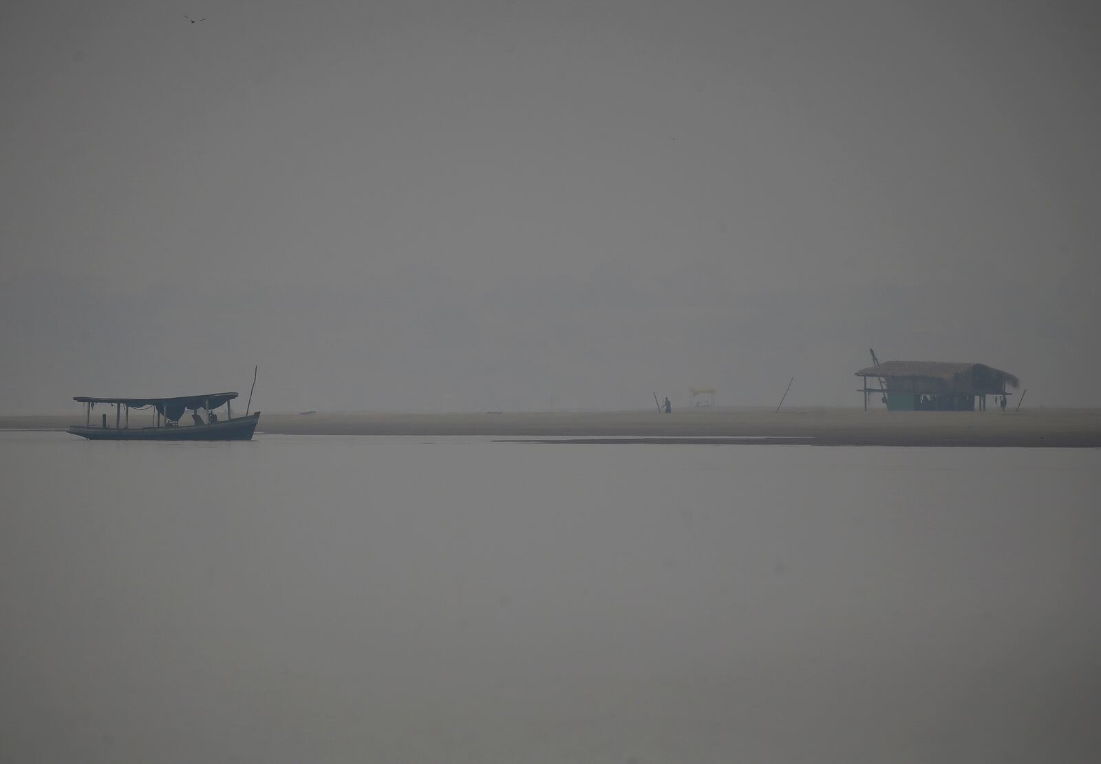 A man traverses smoke from wildfires near the Madeira River, a tributary of the Amazon River, during dry season in Humaita, Amazonas state, Brazil, Saturday, Sept. 7, 2024. (AP Photo/Edmar Barros)