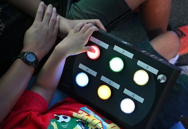 Summer camp participant Toby, 8, plays and learns using technology as his brother and volunteer Josiah (left), 12, assists in sensory room during a summer camp for children with special needs at Lekotek of Georgia in Tucker on Tuesday, July 12, 2022. (Hyosub Shin / Hyosub.Shin@ajc.com)