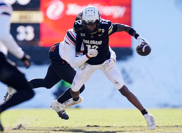 Colorado wide receiver Travis Hunter, front, is tackled after pulling in a pass by Oklahoma State safety Kobe Hylton in the first half of an NCAA college football game Friday, Nov. 29, 2024, in Boulder, Colo. (AP Photo/David Zalubowski)