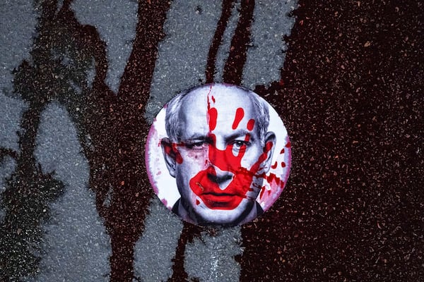 FILE - Supporters of Israelis held hostage by Hamas in Gaza stuck a sticker with the face of Israeli Prime Minister Benjamin Netanyahu on a road and poured red liquid, symbolizing blood, over it, in Jerusalem, Feb. 17, 2025. (AP Photo/Ohad Zwigenberg, File)