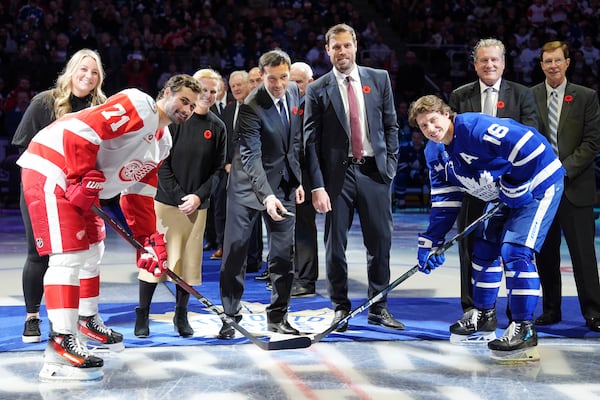 2024 Hockey Hall of Fame inductees Krissy Wendell-Pohl, from back left to right, Natalie Darwitz, Pavel Datsyuk, Shea Weber, Jeremy Roenick and David Poile pose for a ceremonial face off photo with Detroit Red Wings' Dylan Larkin (71) and Toronto Maple Leafs' Mitch Marner (16) during a ceremony prior to NHL hockey game action in Toronto, Friday, Nov. 8, 2024. (Frank Gunn/The Canadian Press via AP)