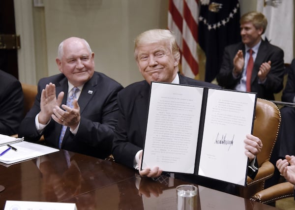 In this 2017 photo, U.S. Agriculture Secretary Sonny Perdue looks on as then-President Donald Trump signs an order. Perdue, now chancellor of the University System of Georgia, has declined to comment on the upcoming presidential election. (Olivier Douliery/Abaca Press/TNS)