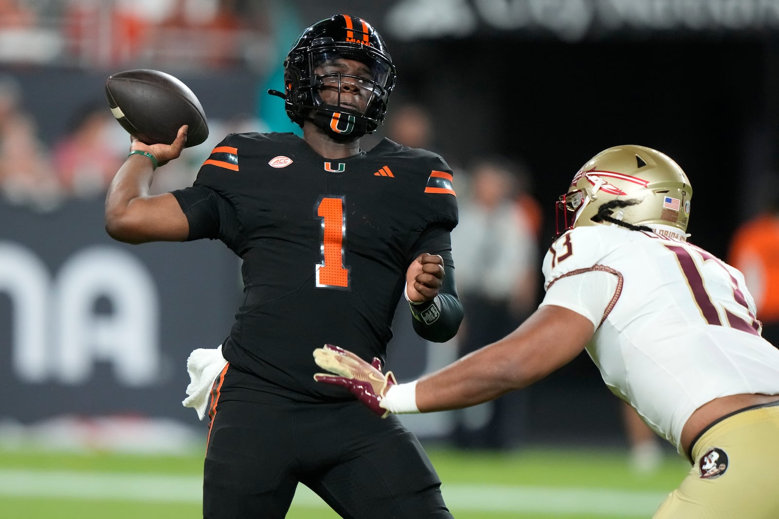 Miami quarterback Cam Ward (1) looks to pass as Florida State defensive lineman Sione Lolohea (13) defends during the first half of an NCAA college football game, Saturday, Oct. 26, 2024, in Miami Gardens, Fla. (AP Photo/Lynne Sladky)