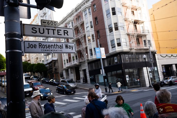 People gather by the street sign Joe Rosenthal Way, that honors the former AP photojournalist who the Pulitzer Prize for his iconic photo of U.S. Marines raising the flag on the Japanese island of Iwo Jima during WWII, Thursday, Dec. 12, 2024, in San Francisco. (AP Photo/Minh Connors)