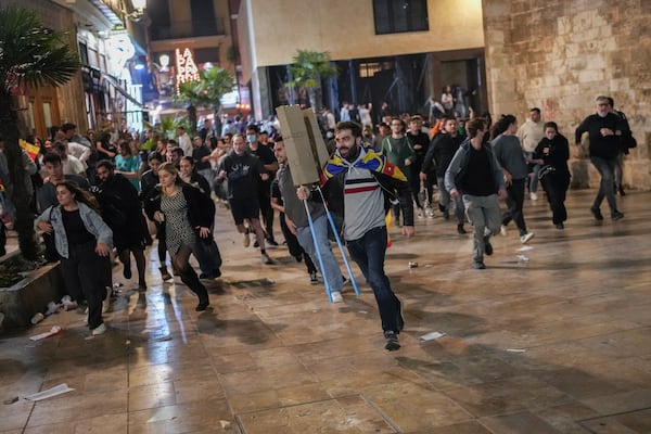 Demonstrators run away from riot police during minor clashes after a peaceful protest organized by social and civic groups, denouncing the handling of recent flooding under the slogan "Mazon, Resign," aimed at the president of the regional government Carlos Mazon, in Valencia, Spain, Saturday, Nov. 9, 2024. (AP Photo/Emilio Morenatti)