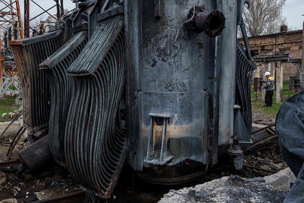 A worker of DTEK company walks in front of a transformer of a substation destroyed by a Russian drone strike in undisclosed location, Ukraine, March 25, 2025. (AP Photo/Evgeniy Maloletka)