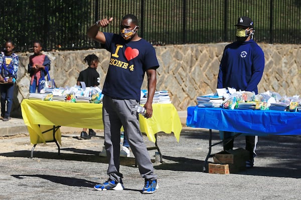 Ian Elmore-Moore indicates that the volunteers are ready to begin the Grab and Go free food and groceries event on Friday, April 17, 2020, at Allen Hills Apartments in Atlanta. Fulton County prosecutors Shari Jones, Brandon Pierre Thomas and Terrell Thomas are part of a community effort to distribute grocery items at Allen Hills. (Christina Matacotta, for The Atlanta Journal-Constitution)