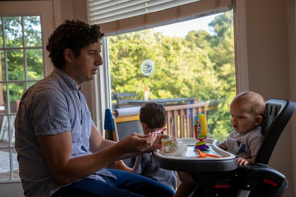 Tommy Beeson, husband of Democratic state Senate candidate Sarah Beeson, feeds their youngest son Rowan (right) during dinner time at their residence in Roswell on Sept. 10, 2020. Tommy helps Sarah by keeping the kids busy in the basement as she participates in campaign events in the evening. (Alyssa Pointer / Alyssa.Pointer@ajc.com)