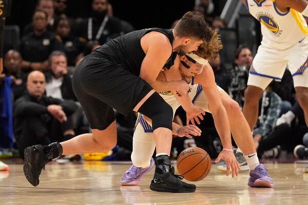 Cleveland Cavaliers guard Ty Jerome, left, and Golden State Warriors guard Brandin Podziemski, right, reach for the ball in the first half of an NBA basketball game, Friday, Nov. 8, 2024, in Cleveland. (AP Photo/Sue Ogrocki)