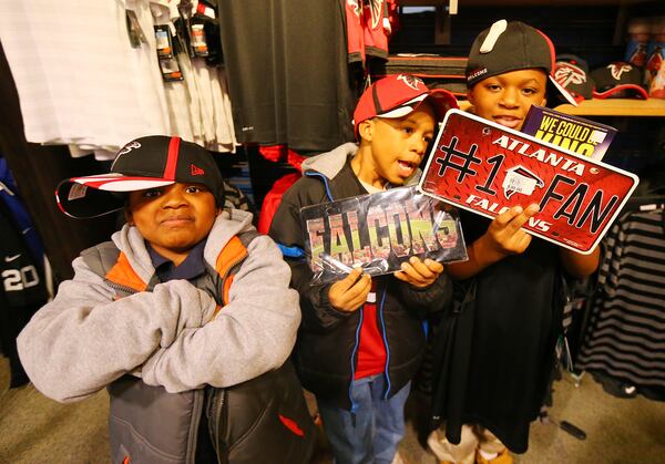 Corde Astro, 7, (from left) Quinntavious Harkness, 8, and Khalic English, 9, from the Atlanta Action Ministries, check out the Falcons items while cruising the store with rookie lineman Jake Matthews on a Christmas shopping spree at Dick's Sporting Goods on Tuesday, Dec. 16, 2014, in Duluth. CURTIS COMPTON / CCOMPTON@AJC.COM