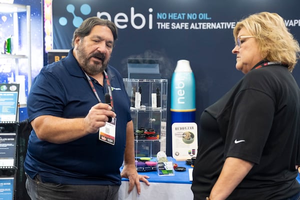 Mauricio Amaya, left, shows off a tool like a nebulizer for taking his company's CBD-derived product while working at the Synergy Life Sciences booth at the Alternative Products Expo in Atlanta on Friday, Oct. 11, 2024. The company's CEO says regulation is so confused that they are paying hundreds of thousands of dollars for a scientific safety company to test their products and get an independent seal of approval they hope will keep their product above the fray.    (Photo by Ben Gray for The Atlanta Journal-Constitution)