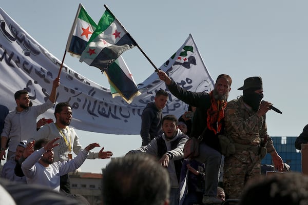 Syrians wave their new national flags, as they shout slogans to show their solidarity with the government security forces during a protest in Damascus, Syria, Friday, March 14, 2025. (AP Photo/Omar Sanadiki)