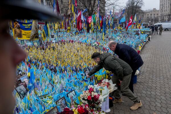 Ukraine's President Volodymyr Zelenskyy, left, and German Chancellor Olaf Scholz attend a ceremony of honoring fallen soldiers near the People's Memorial of National Memory in Kyiv, Ukraine, Monday, Dec.2, 2024. (AP Photo/Evgeniy Maloletka)