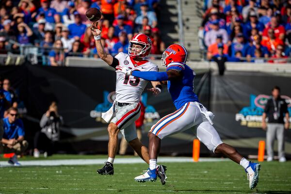 Georgia quarterback Stetson Bennett (13) scrabbles out of the pocket while being defended by Florida linebacker Jeremiah Moon (7) during the first half of an college football game, Saturday, Oct. 30, 2021, in Jacksonville, Fla. (Stephen B. Morton/Atlanta Journal-Constitution)