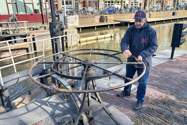 Rashid Ouchene opens the lock in Utrecht, Netherlands, Tuesday, March 11, 2025, where a "fish doorbell" was installed that lets viewers of an online livestream alert authorities to fish being held up as they make their springtime migration to shallow spawning grounds. (AP Photo/Aleksandar Furtula)