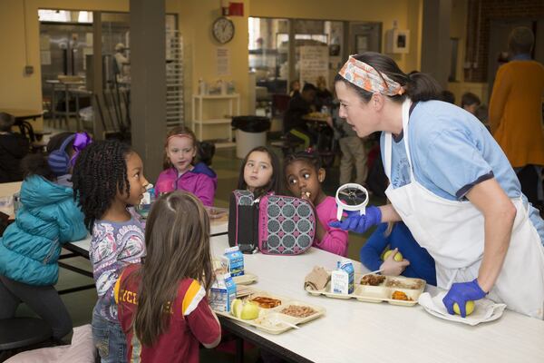 Students must be offered a serving of fruit with every meal. Kelli Dyer offers to core and slice the apples these elementary school students will enjoy with their lunch. Photo: Kelley Klein