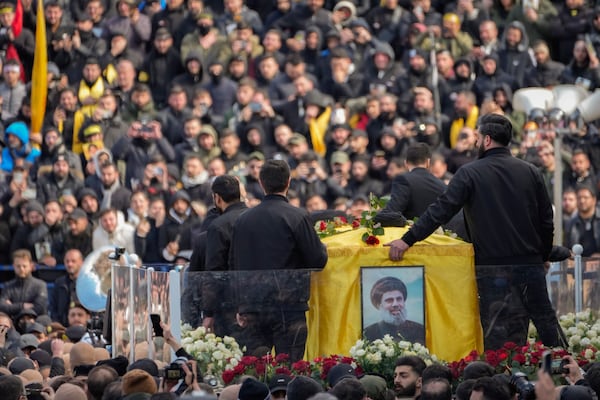 A trailer carrying the coffins containing the bodies of Hezbollah's former leader Hassan Nasrallah and his cousin and successor Hashem Safieddine drives through the crowd at the beginning of a funeral procession in the Sports City Stadium in Beirut, Lebanon, Sunday, Feb. 23, 2025. (AP Photo/Hussein Malla)