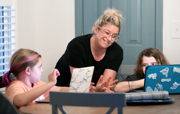 Caitlin Snyder reacts as she helps her two daughters Zoie (left), 9, and Ryleigh, 10, while they are being homeschooled on Wednesday, Aug. 25, 2021. The parents pulled them out of Kemp Elementary in Cobb County because the district has no mask mandate and they could not enroll in virtual classes. (Hyosub Shin / Hyosub.Shin@ajc.com)