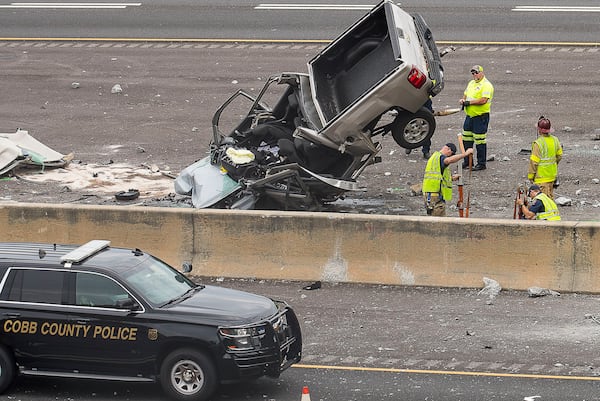 Cobb County firefighters work to clear the wreckage after a pickup truck ran through a concrete wall on Akers Mill Road and plunged onto I-75.